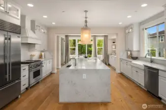 The dream kitchen boasts a dramatic waterfall island, Wolf appliances, a Sub-Zero refrigerator, upgraded  cabinetry, a butler’s pantry, and more!