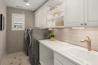 Spacious laundry with fully tiled backsplash and side wall, lighted cabinets, utility sink and extra storage!