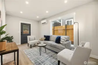 The great room has a large window and has a second door leading to the patio. You will see one of the mini split heat pumps that heats and cools the home.