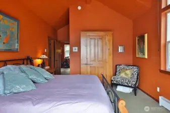 Primary bedroom with vaulted ceilings, transom windows and French doors to upper deck.  Baseboard heater is "Soft Heat" in addition to ductless mini split.