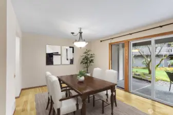 Formal dining room with light pouring in from the wall of windows. Virtually staged.
