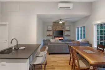 Open-concept living area connects seamlessly to the kitchen and dining space, featuring large windows that bring in natural light and forest views.