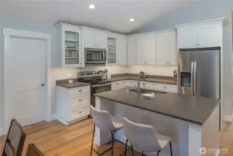 Stylish kitchen with crisp white cabinetry, stainless steel appliances, and spacious peninsula with bar seating—ideal for everyday living and entertaining.