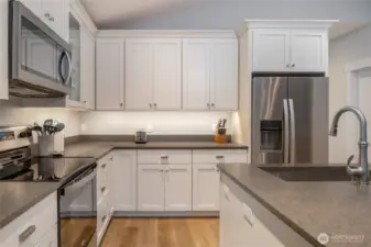 Well-equipped kitchen with stainless steel refrigerator, range, microwave, and dishwasher, surrounded by generous cabinetry and counter space.