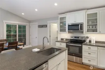 Large center island with undermount sink provides extra prep space and casual seating, complemented by abundant cabinetry and under-cabinet lighting.