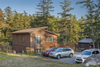 Modern island home surrounded by mature evergreens with ample parking and easy access to the main entrance. The natural wood siding blends beautifully with the forested surroundings for a true Pacific Northwest aesthetic.