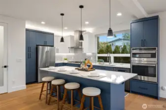 A wow kitchen with quartz counter tops, glass tile backsplash, massive storage space and just to the left- the door goes the walk-in pantry space.