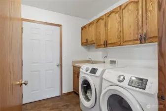 Full laundry room located as you come into the house from the garage, with the added bonus of a utility sink and cabinetry.