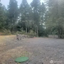 View from pump house shows rock wall between upper and lower areas of lot. Privacy fence at each end of lot.