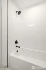 Full height tile tub/shower surround in first level bathroom.  Photos are staged model of similar floorplan. Color scheme and layout will differ.