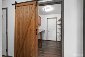 Sliding barn door into laundry/pantry room with door to garage.
