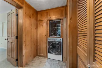 Washer and dryer combo + built in Wine Fridge. To the right is additional pantry storage. To the left is the entrance to the primary bedroom.