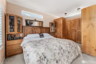 Spacious primary bedroom offers a peaceful retreat with abundant natural light and an open walk-in closet featuring custom cabinetry for organized, stylish storage.
