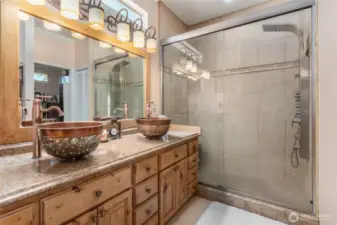 Bathroom features warm copper sinks paired with a spacious walk-in shower