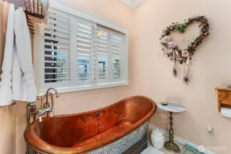 Relax and unwind in the primary bath’s beautiful copper clawfoot tub, offering a luxurious soaking experience.