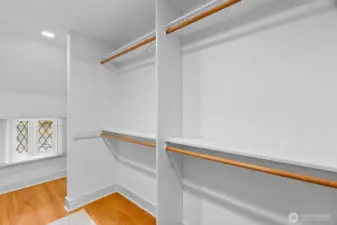 Spacious walk-in closet in the primary suite is highlighted by the original lead-paned window.