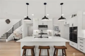 Kitchen Island View: Expansive center island with quartz countertops, pendant lighting, and seating for three, offering both function and a gathering spot. The open design highlights the chef’s kitchen and adjacent living areas.  Staged photos are of the model home of the same floorplan within the Foxmoore community and are for visualization purposes only. Colors, finishes, and layout can and will vary.