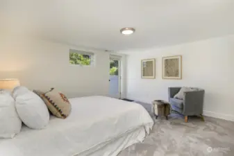 This bedroom has a glass door that opens out onto the fenced backyard. Its windows face east.