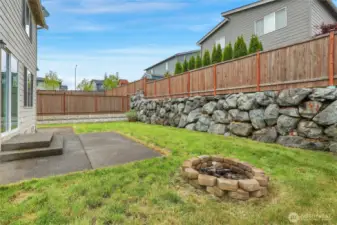Nice rock retaining wall and everone enjoys a little backyard fire pit!