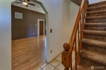 Warm and welcoming entryway with tile floors, plush carpeted stairs, and a peek into the open living space your next chapter starts right here