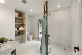 Beautiful artisan-style primary bathroom featuring a spacious walk-in shower with custom tilework and dual pedestal sinks. Thoughtfully designed with natural textures and modern lighting for a clean, spa-like retreat