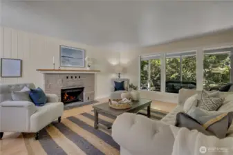 Cozy stone fireplace looking out to covered deck & forestland. All freshly painted; hardwood floors.