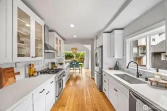 Modern kitchen design with quartz counters, glass cabinets and wide-plank oak flooring.