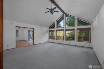 Living room with vaulted ceilings and wall of windows.