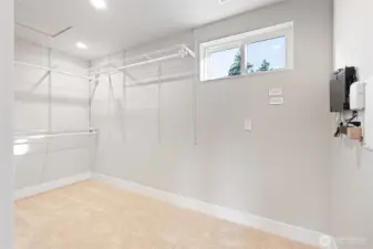 Huge walk-in closet with a window and built-in shelving and hangers.