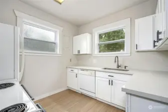 Newly remodeled kitchen with white cabinets, quartz countertops and vinyl plank flooring.