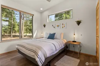 Primary bedroom with serene forest views and modern finishes.