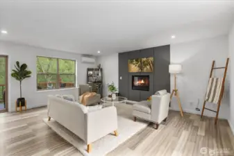 Windows flood the living area with light, showcasing the surrounding trees and forest.