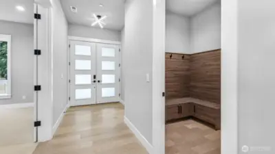 Upon entering through the front double doors, you have the den to your left, a powder room to the right, as well as a mud room and access to the garage (in this photo).