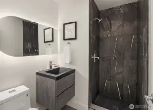Hall bathroom with large shower stall and natural stone tile