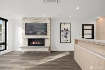 Looking across the living room with the gas fireplace that has a television mounted above that looks like art, when not in use.