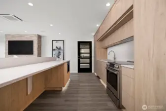 Looking through the kitchen to the door that leads out to the covered and heated outdoor living space. Notice the large eating bar with a built-in microwave beyond.