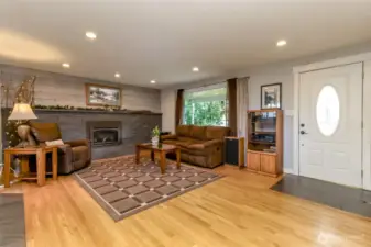 As soon as you step through the door, warmth greets you from the gleaming hardwood floors. The centerpiece is the full wall gas fireplace. A flood of natural light streams in brightening the space and highlighting the rich tone of the wood and stone. The open concept layout seamlessly connects living areas, creating an airy, welcoming flow that makes the home feel instantly inviting.