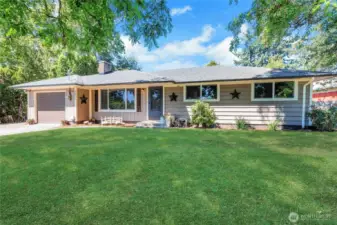 Framed by shade trees and lush green lawn, this angle showcases the home’s symmetrical charm, architectural simplicity, and a welcoming entry. It’s the kind of place that feels like home the moment you arrive.