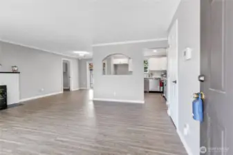 Step inside to an inviting open-concept layout with stylish laminate wood flooring and a soft gray palette that flows seamlessly throughout. The arched pass-through offers charming visibility into the kitchen, blending classic character with modern updates.