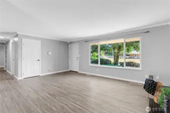 A second look at the bright and airy living space, showcasing the expansive picture window that frames the lush front yard and tree-lined street. Ample space to relax, host, or work from home in comfort.