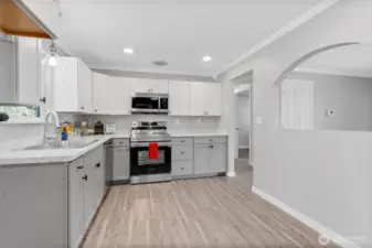 This freshly updated kitchen shines with sleek stainless steel appliances, quartz-style countertops, and shaker cabinets. The arched opening provides a visual connection to the living area while keeping kitchen activity tucked away.