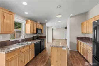 Spacious, open-concept kitchen featuring natural wood cabinetry, durable countertops, and a large center island—perfect for cooking and entertaining. This energy-efficient home in Lacey’s 55+ Lakeview Meadows community offers both beauty and functionality.