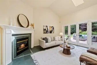 Family room off the kitchen with slate floors, gas fireplace, vaulted ceilings, skylight and French doors opening to the backyard deck and large level backyard.