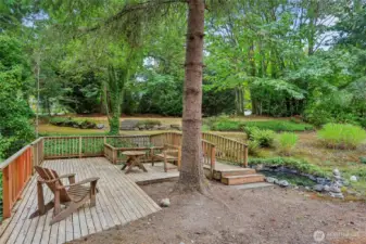 Charming outdoor seating area for morning coffee or entertaining, complemented by your own private pond and a stream that flows in winter
