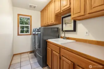 Convenient Upper-Level Laundry Room with sink and storage cabinets