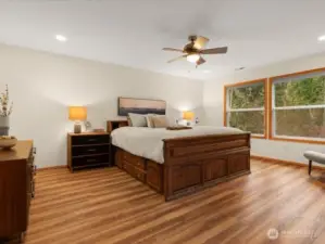 Sizable primary suite, with adjoining office, offers a ceiling fan and oversized windows to maximize the picturesque backyard views