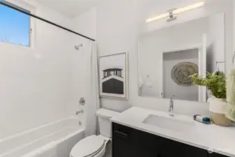 Fresh and functional, the second bathroom features a clean design with a full tub, modern fixtures, and charming accents.
