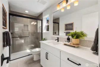 Large lower level bathroom, with a shower and white and grey marble-look quartz countertops.