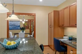 The large pantry on the right and cabinets above the built-in desk provide plenty of storage options.