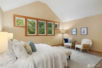 Another view of the primary bedroom highlighting the large bank of windows.